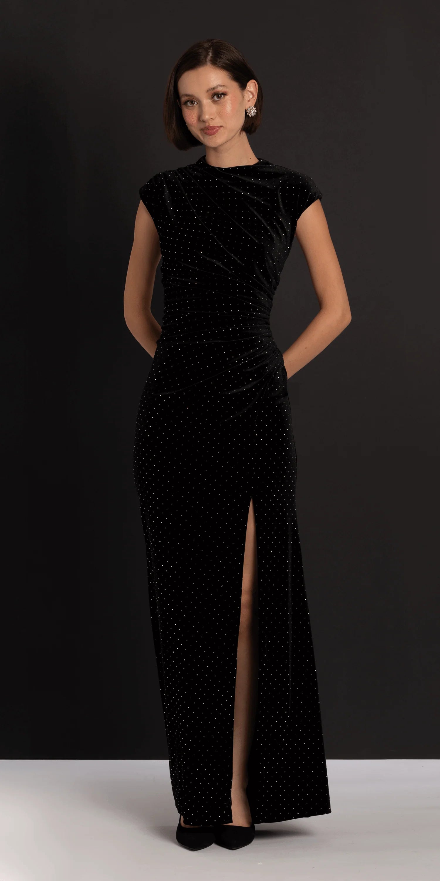 Elegant black velvet evening dress with cap sleeves, mock neck, ruched waist, and floor-length skirt with slit